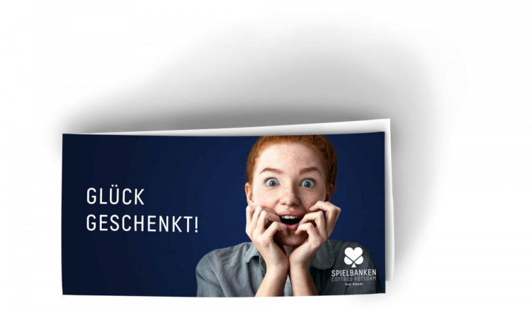 Zu sehen ist ein Foto des Gutscheins für die Spielbanken Potsdam und Cottbus. Das zusammengeklappte Format des Gutschein ist Din lang. gefalzt ist er an der linken kurzen Seite. Er ist blau und darauf abgebildet eine junge Frau mit roten, zu einem Dutt hochgebunden Haaren, die beide Hände freudig überrascht an den leicht geöffneten Mund legt. Auf dem Gutschein steht links in Großbuchstaben Glück Geschenkt.